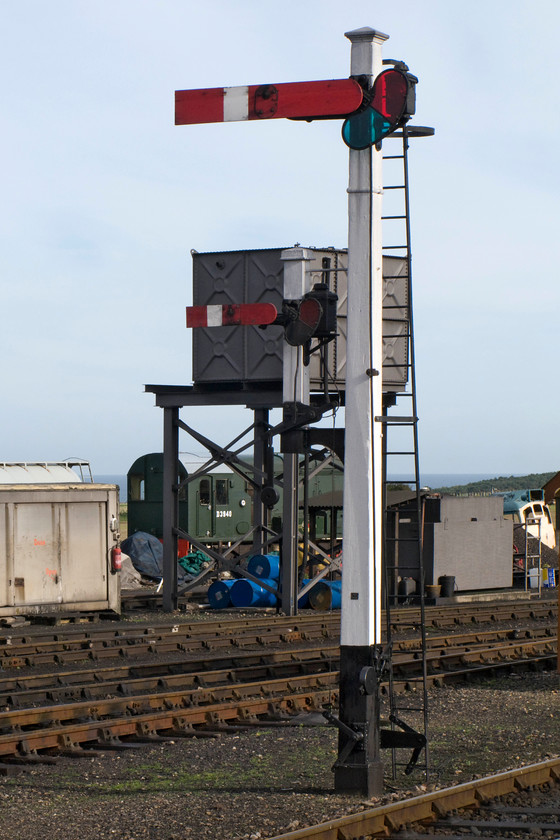 D3940, stabled, Weybourne yard 
 With the North Sea in the background, the view looking across Weybourne yard sees one of the NNR's resident shunters behind the water tower. D3940 was built at Derby in 1960 and was initially allocated to York. Later it moved to Gateshead, Percy Main (Jarrow) and Thornaby where it was withdrawn in 1994. Dominating this photograph is the superb GE wooden somersault bracket signal to the eastern end of Weybourne station. The main arm is the station starter and the submissive arm permits access to the yard 
 Keywords: D3940 Weybourne yard shunter class 08 sumersault signals