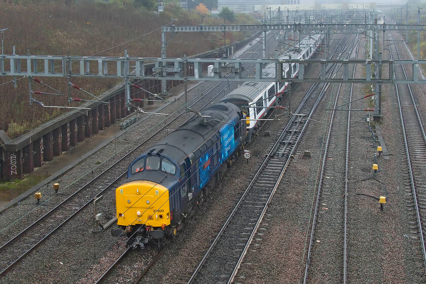 37800, 321301 & 321324, 09.18 Wembley Yard-Wolverton Centre Sidings (5J70, 25L), Loughton Redway bridge, Milton Keynes 
 After being brought to almost a complete halt just south of Milton Keynes station the drive of 37800 'Cassiopeia' was certainly being a little enthusiastic with the power handle as he got his train underway again! This was a little surprising as the 5J70 09.18 Wembley Yard to Wolverton Centre Sidings only had a couple of miles before reaching its destination! Long-term Wembley Yard residents former Greater Anglia 321301 and 321324 were being taken to Wolverton for possible future use rather than scrapping but I am unsure as to what this use could be. 
 Keywords: 37800 321301 321324 09.18 Wembley Yard-Wolverton Centre Sidings 5J70 Loughton Redway bridge Milton Keynes Cassiopeia