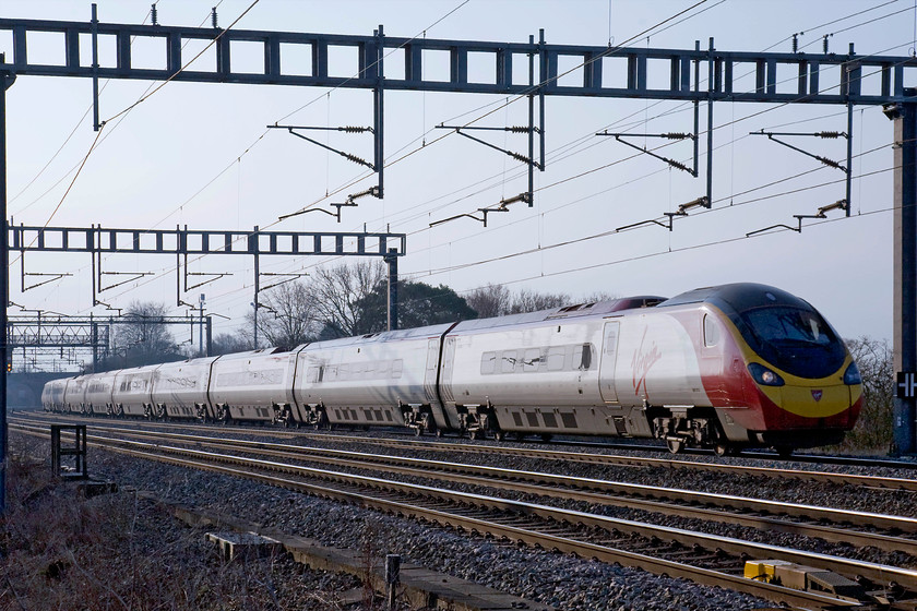 390013, VT 07.30 London-Euston-Glasgow Central (9S42), Ashton Road bridge 
 The first down Scottish express of the day is about to pass Roade in Northamptonshire formed by 390013. The 9S42 07.30 Euston to Glasgow Central arrives into its destination in the late morning. Notice the strange sign attached to the electrification post indicating to track workers that clearance is very tight with no safe walkway. 
 Keywords: 390013 07.30 London Euston-Glasgow Central 9S42 Ashton Road bridge