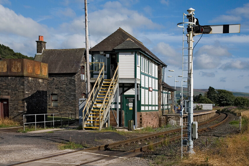 Foxfield signal box (Furness, 1879) 
 My first visit to Foxfiled since 1979, see... https://www.ontheupfast.com/p/21936chg/26718012404/m56250-m50947-14-40-barrow-furness and am delighted to see that it has not changed a great deal. The BR (London Midland) enamel nameplate that used to hang above the door has gone with a replacement replica wooden one on the face of the box. The box is a Furness. Also notice that the steps have been replaced and a small personal needs facilty added to the end of the box. What is nice, however, is that this has been blended, including the slate roof, to match the rest of the box; something that does not happen very often today. 
 Keywords: Foxfield signal box Furness, 1879