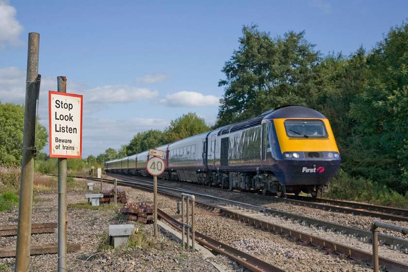 43016, GW 11.33 London Paddington-Exeter St. David s (1C81), Blatchbridge Junction 
 Knowing that the majority of the HST on the down fast line at Blatchbridge Junction would be in the shade not only because of the trees but also as I have moved to the other side of the line putting the sun on the wrong side, I opted for a more creative photograph. I exposed and focussed on the signage at the foot crossing where I was standing thus putting the subject mildly out of focus. 43016 leads the 11.33 Paddington to Exeter St. David's at speed as it leaves the Frome cutoff to continue its journey westwards. The cutoff was opened in 1933 as part of a suite of measures introduced by the GWR to improve their West of England services that left Frome a little isolated on a branched loop. 
 Keywords: 43016 11.33 London Paddington-Exeter St. David's 1C81 Blatchbridge Junction FGW First Great Western HST