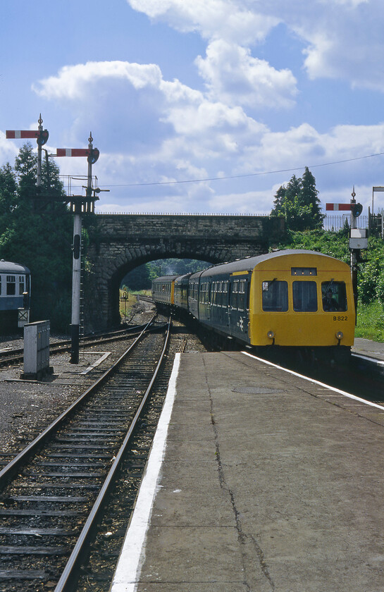 B822, 13.00 Weymouth-Westbury, Yeovil Pen Mill station 
 This photograph marks the move from the dependable Ilford FP4 rated at 125 ASA with its soft tones and forgiving tonal range which means that in the modern era it is very easy to scan and work with in Photoshop. Due to a teenage lad's money-saving strategy, I decided to use a series of Fujichrome 100 films instead of the more normal Kodachrome 64. Whilst I would have welcomed the improvement in film speed looking back now it is clearer that the cheaper film was inferior in many respect to the Kodak and Ilford products. The images have an unfortunate hue and a propensity to be a little over-exposed and washed out. Modern-day scanning and use of Photoshop have needed a lot of extra work to get the images back to an acceptable standard for both myself and for presentation on the website. At Yeovil Pen Mill station a Class 101 DMU, set B822 (composed of what should have been W51495, W59096 and W51510) leads another unit in with the 13.00 Weymouth to Westbury service. 
 Keywords: B822 13.00 Weymouth-Westbury Yeovil Pen Mill station