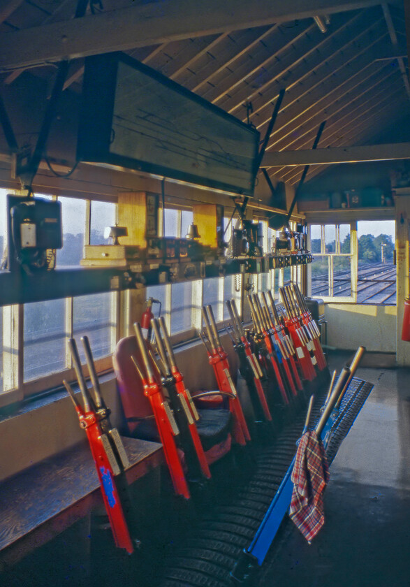 Interior, Witham signal box 
 The interior of Witham signal box is seen as the sun sets on a well-remembered Royal Wedding day. I know very little about the history of the box with very little actually documented about it. The sixty-one lever frame seems to have had a number removed. The box closed on 26.11.84 with control moving to Westbury PSB. Demolition came during the spring of 1985 bringing down another era in our railway heritage. 
 Keywords: Interior Witham signal box