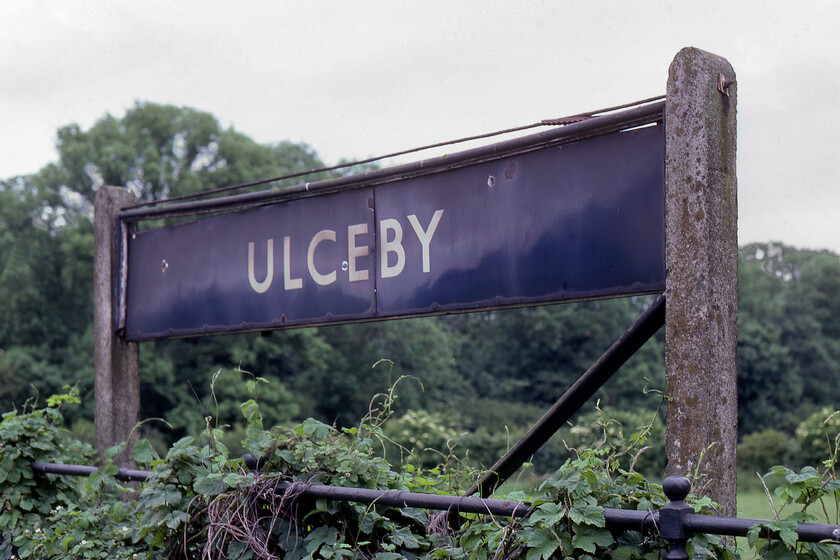 Enamel, Ulceby station 
 Ulcbey station is located on the northern apex of a triangle of lines in north Lincolnshire. It is one of three stations (with one now closed) located at the other points of the triangle with Habrough to the east and Brocklesby to the west (closed 03.10.93). Back in 1981 all the stations and the infrastructure were delightfully quaint with much appearing to be forgotten in what appeared to be a railway backwater. This did mean that there was much to photograph delighting the railway enthusiast such as BR enamel signs. This particular example at Ulceby looks as if it is about to fall into the brambles and bindweed enveloping the railings below! As with the sign at Brockelsby taken a little earlier, I am not sure if this example was a BR blue or an LNER example, I suspect the latter but will take advice from my reader! 
 Keywords: Enamel, Ulceby station