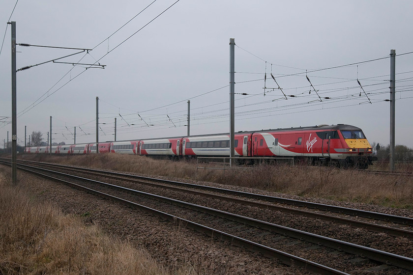 82217 & 91106, GR 05.48 Edinburgh Waverley-London Kings Cross (1E02, RT), Woodcroft Crossing TF139050 
 I very overcast conditions at the beginning of January, the 05.48 Edinburgh to London King's Cross approaches Peterborough passing Woodcroft crossing. DVT 82217 is on the front with 91106 '#GetNorth2018' pushing on the rear. We were kept here at Woodcroft crossing, situated on the minor road between Marholm and Etton, for some time due to the passage of trains. It's a manual manned crossing with the gatekeeper taking his instructions from Helpston box some mile or so to the north. 
 Keywords: 82217 91106 1E02 Woodcroft Crossing TF139050