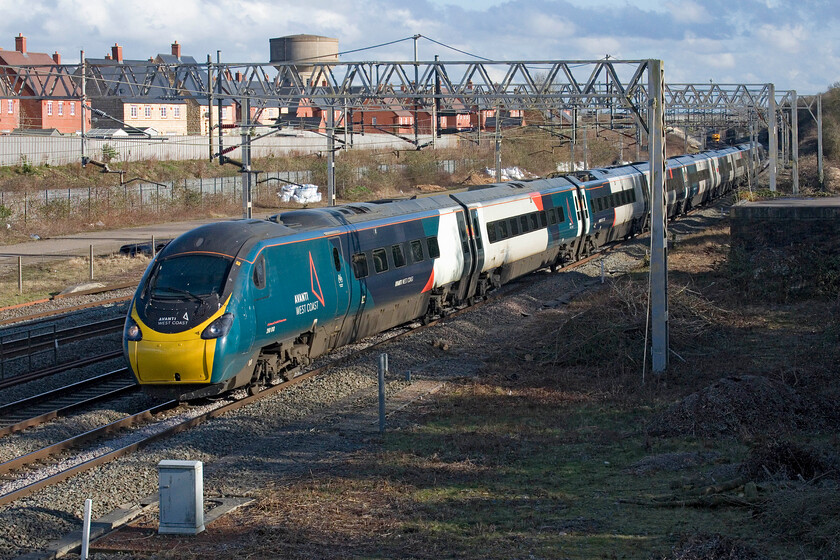 390010, VT 15.16 London Euston-Preston (9S58, 7L), site of Roade station 
 With the decision on Avantis West Coast future due any day now there is a distinct possibility that the operator will be stripped of its franchise with a new operator to put its mark on the Class 390 Pendolinos. 390010 Cumbrian Spirit passes the site of Roade station working the 9S58 15.16 Euston to Preston service. Notice the flash of yellow in the background, something far more interesting and unusual was about to pass on the down slow line.....

NB it was announced on Monday 20.03.23 that AWC would be awarded a six-month extension to its franchise. This was very much against expectations given its shambolic management of operations over the last year or so and further goes, in my mind at least, to illustrate how broken and ineffective the franchising model is. 
 Keywords: 390010 15.16 London Euston-Preston 9S58 site of Roade station Avanti West Coast AWC PendolinoCumbrian Spirit