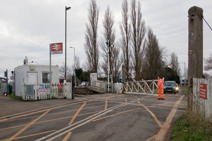 Opening the crossing gates, Whittlesea level crossing 
 After the passage of the 07.54 Newcastle to King's Cross, the crossing keeper opens the gates for road users. Notice his small portacabin to the left that is interlinked to the signal box at the other end of the slewed station platforms. This signal box controls the semaphores. 
 Keywords: Opening the crossing gates Whittlesea level crossing