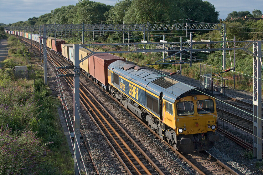 66708, 03.10 Felixstowe North-Trafford Park (4M18, 5E), site of Roade station 
 66708 'Jayne' leads the 4M18 03.10 Felixstowe North to Trafford Park service past the site of Roade's former station on this bright August morning despite the cloud already beginning to fill the sky. The land to the left of this photograph was once filled with numerous sidings most of which served the large adjacent Pianoforte factory site that, despite its name, between 1939 and 1945 produced large amounts of munitions for the war effort reverting back to the production of car parts until closure came in 2008. The factory site is now covered by a large new housing estate. 
 Keywords: 66708 03.10 Felixstowe North-Trafford Park 4M18 site of Roade station GBRf GB Railfreight Jayne