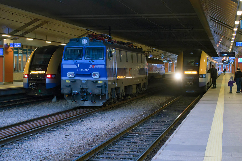 EN77-004, 17.21 Krakw Glwny-Sedziszw (KML32822), EP09-003 & EN77-005, 17.22 Krakw Glwny-Tarnw (KML33421), Krakw Glwny station 
 Between duties, EP09-003 sits in Krakw's Glwny station between a pair of Malopolskie province operated Class EN77 Acatus 2 EMUs. To the left, EN77004 will leave with the 17.21 to Sedziszw a small town due north of Krakw. Meanwhile to the right, sister unit EN77005 will leave a minute later with the 17.22 to Tarnw a large and historic town to the south-east of the city. 
 Keywords: EN77-004 17.21 Krakw Glwny-Sedziszw KML32822 EP09-003 EN77-005 17.22 Krakw Glwny-Tarnw KML33421 Krakw Glwny station PKP Polish Railways