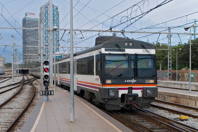 470 039, Renfe unidentified working, Barcelona Frana station 
 Re-built from the Class 440 units in the mid-1990s the fifty-seven Class 470s are used on many inner and outer suburban services. 470 039 enters Barcelona Frana station with an unidentified working. This photograph clearly shows the wider Iberian (1,668 mm) used in much of Spain. It may appear that standing on the platform end of Frana station I would be immersed in the zounds of the surrounding city but it felt more like being in a rainforest with Barcelona zoo being just across the tracks to my left and it must have been feeding time judging by the sounds emanating from it! 
 Keywords: 470 039 Renfe unidentified working Barcelona Frana station