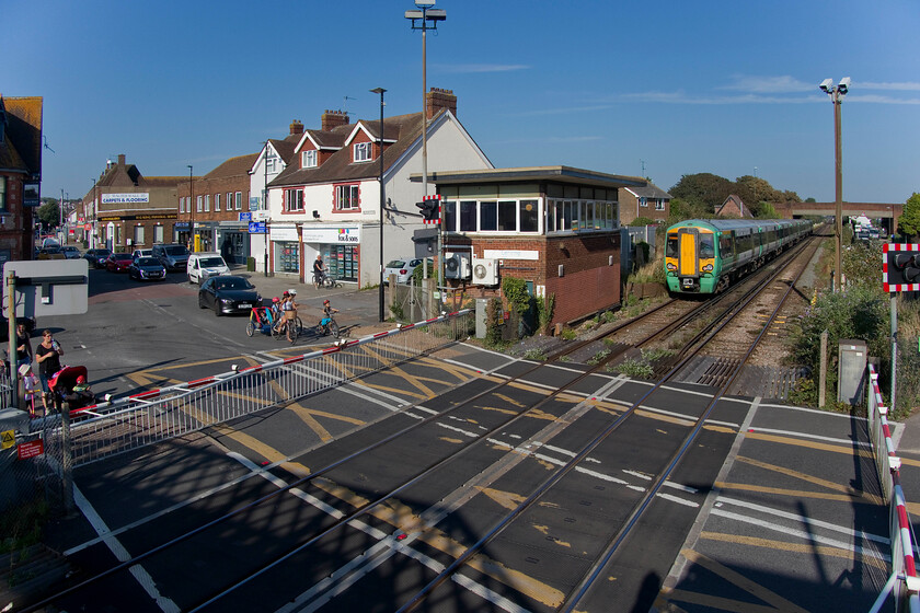 377468, SN 16.13 Littlehampton-London Victoria (1H47, 1E), Lancing level crossing 
 A wide-angled view taken from the pedestrian footbridge to the east of Lancing station reveals the busy level crossing with South Street. Centre in the image is the 1963 British Railways built signal box that is still in use but to what degree I am unsure; local knowledge, please? 377468 has just sped through the station a short distance into its journey, the 1H47 Littlehampton to Victoria Southern service. 
 Keywords: 377468 16.13 Littlehampton-London Victoria 1H47 Lancing level crossing Southern Electrostar