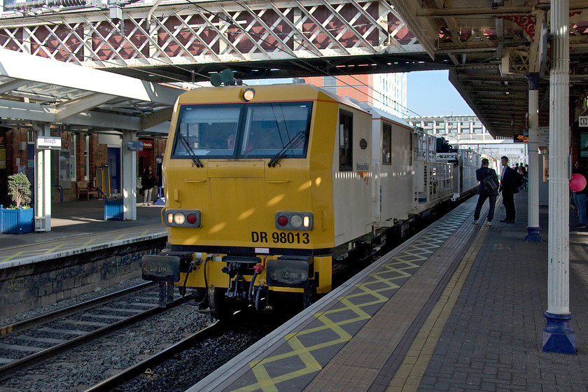 DR 98013, 11.54 Chelmsford-Swindon Transfer, Slough station 
 The 11.54 Chelmsford to Swindon Transfer engineer's train passes through Slough station. It is being led by DR 98013 'David Wood'. The train was composed of a number of assorted HOOB wagons. I was surprised at the speed this train was travelling that only allowed me to capture the shaded part of the station; I had no time to get to a sunny spot from when the announcement made that 'the train passing platform four is not scheduled to stop' and to 'stand clear' was made. 
 Keywords: DR 98013 11.54 Chelmsford-Swindon Transfer Slough station