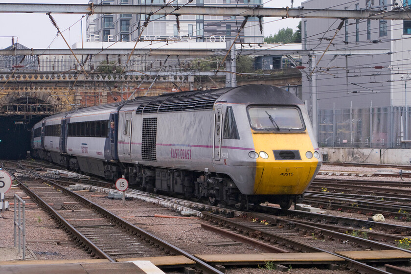 43315, GR 06.55 Skipton-London King's Cross (1A13), London KIng's Cross station 
 43315 leads the 06.55 Skipton to King's Cross East Coast service out of Gasworks tunnel into the light approaching its destination. The large utilitarian structure to the right is King's Cross PSB that is due to close sometime in the not too distant future as Network Rail continues to roll out its grand plan to have just a handful of regional signalling centres controlling the entire network. 
 Keywords: 43315 06.55 Skipton-London King's Cross 1A13 London KIng's Cross station East Coast HST