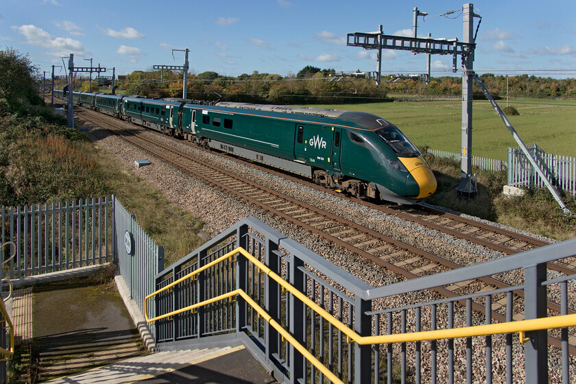 800320, GW 12.00 Bristol Temple Meads-London Paddington (1A19, RT), South Marston SU193869 
 800320 working the 12.00 Bristol Temple Meads to Paddington GWR service passes a new footbridge installed at South Marston just west of Swindon. The bridge is just over seventy-four miles from Paddington and is curiously numbered MLN 1. Behind the trees in the background lies the remains of the huge Honda car factory that closed in 2020 that has all but been cleared and is destined to become a large-scale logistics hub that may well make use of the rail link installed to serve the Honda plant back in the 1990s. 
 Keywords: 800320 12.00 Bristol Temple Meads-London Paddington 1A19 South Marston SU193869 GWR IET