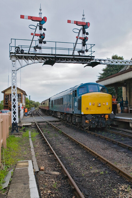 45133, 08.55 Peterborough Nene Valley-Wansford (2M42), Wansford station 
 Passing under Wansford's impressive signal gantry 45133 arrives at the station leading the 08.55 from Peterborough Nene Valley. The Peak is another visitor to the line being owned by the Class 45/1 Preservation Society. 
 Keywords: 45133 08.55 Peterborough Nene Valley-Wansford 2M42 Wansford station Peak