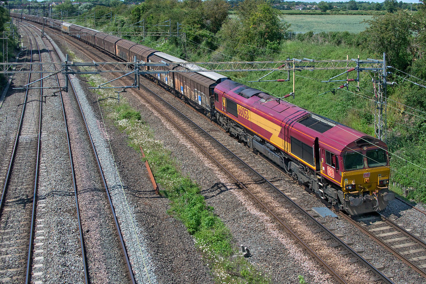 66053, 14.41 DIRFT-Dollands Moor (6O67, 83E), Victoria bridge 
 Despite its rather faded EWS paintwork, I am pleased to have a photograph of 66053 working the 6O67 Daventry to Dollands Moor empty vans. This is because this particular 1999 example is a photographic cop. The train is seen passing Victoria bridge between Northampton and Milton Keynes on a warm and humid summer's afternoon that would soon descend into a very stormy early evening with some dramatic thunderstorms. 
 Keywords: 66053 14.41 DIRFT-Dollands Moor 6O67 Victoria bridge DB EWS