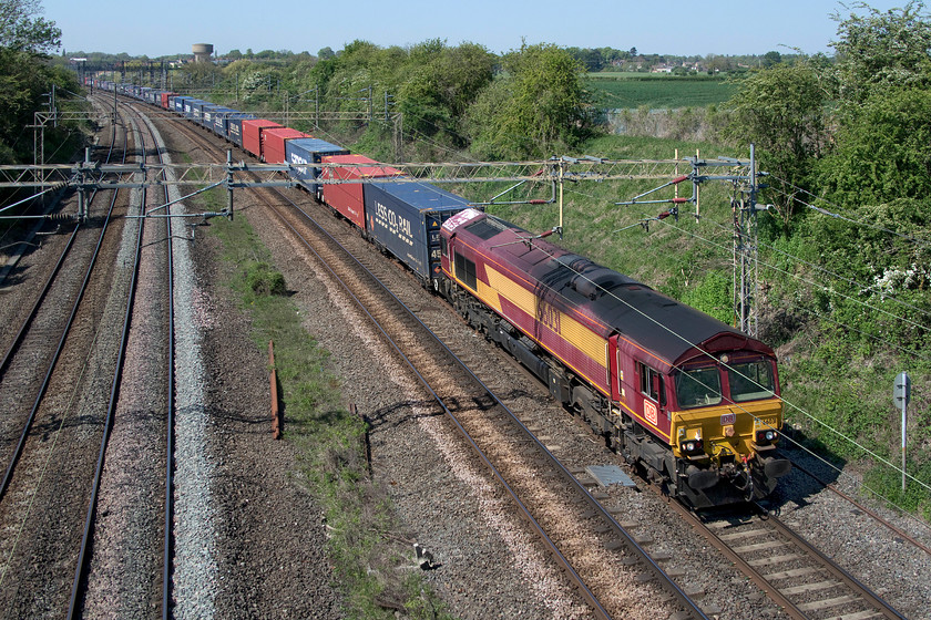 66031, 13.51 DIRFT-Purfleet (4L48, 20E), Victoria bridge 
 The wagons in the consist of the 4L48 13.51 Daventry to Purfleet Freightliner stretch into the distance at Victoria bridge between Roade and Ashton as it heads south. It is being led by a very tatty and faded 66031 that still wears its original EWS livery dating from 1998! However, despite its DB branding since October last year it is in fact operated by DRS so I suspect that it will soon enter the paintshop emerging in a version of its latest blue compass livery that seems to change with pretty frequent regularity. 
 Keywords: 66031 13.51 DIRFT-Purfleet 4L48 Victoria bridge DB EWS Freightliner