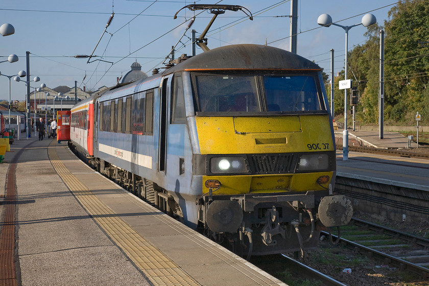 90007, LE 15.00 Norwich-London Liverpool Street (1P43), Norwich station 
 Standing in the warm autumn sunshine at Norwich station is 90007 'Sir John Betjeman'. It is being prepared to work the 15.00 service to London Liverpool Street that will depart in the next five minutes. Notice the huge dome appearing to emerge from the roof of 90007. This dome is the one that greets passengers on arrival at Norwich station that rises above the main concourse. 
 Keywords: 90007 15.00 Norwich-London Liverpool Street 1P43 Norwich station Sir John Betjeman