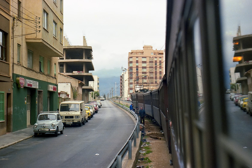 No. 3, unidentified Palma-Sller working, Carrer Concrdia, northern streets of Palma 
 We travelled on the Ferrocarril de Sller (Railway of Sller) all the way from Palma to Sller. This image is taken in the northern suburbs of Palma with the train passing along the Carrer de la Concrdia. We are being hauled by one of the small electrics no. 3. Notice the track workers standing aside as we pass and could that be their van parked in the quiet street to the left? 
 Keywords: No. 3 Palma-Sller working, Carrer de la Concrdia Palma