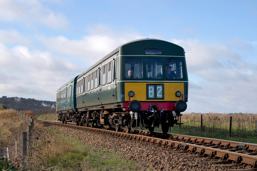 M56352 & M51188, 10.35 Holt-Sheringham, A149 Coast Road bridge 
 Having dropped daily supplies at Weybourne and Holt stations, M56352 and M51188 return with the 10.35 Holt to Sheringham. It is seen about to cross the A149 Coast Road bridge under skies with clouds racing across them on a strong north westerly wind blowing in off the sea. 
 Keywords: M56352 M51188 10.35 Holt-Sheringham A149 Coast Road bridge