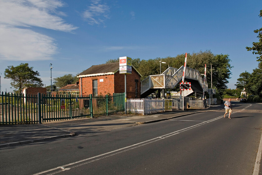 Andy, Hall Road level crossing 
 With the station of the same name in the background, Andy crosses Hall Road West. To the left through the substantial gates was the Hall Road TMD which was originally opened by the LMS in 1939 to provide additional capacity for their new fleet of state-of-the-art Class 502 EMUs that were being delivered at that time. The depot continued in use until 1997 when maintenance became concentrated at Kirkdale and Birkenhead North. After languishing for a number of years it was eventually demolished in 2009 with the land not yet put to further use. 
 Keywords: Andy Hall Road level crossing