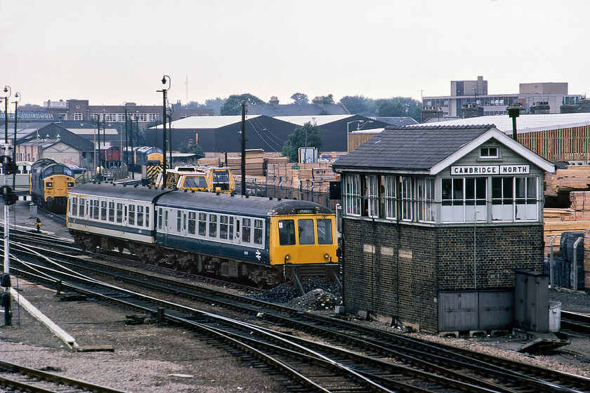 Class 114 DMU & class 37s, stabled, Cambridge North signal box (LNER, 1926) 
 Taken from Cambridge's Mill Road bridge the stabling point is seen along with Cambridge North signal box. In the background, a number of Class 37s are seen that were used extensively on East Anglian services including trains between here and Liverpool Street. The first generation Class 114 DMU stabled displays two liveries indicating that the leading car is unrefurbished with the trailing car having been treated. Cambridge North box is an LNER structure dating from 1926 that was to close two years after this photograph was taken on 16.10.82 with the opening of Cambridge PSB. Notice the extensive timber yard behind the box and sidings, it is still trading today now being Cambridge's branch of Travis Perkins. 
 Keywords: Class 114 DMU class 37s Cambridge North signal box LNER London and North Eastern Railway