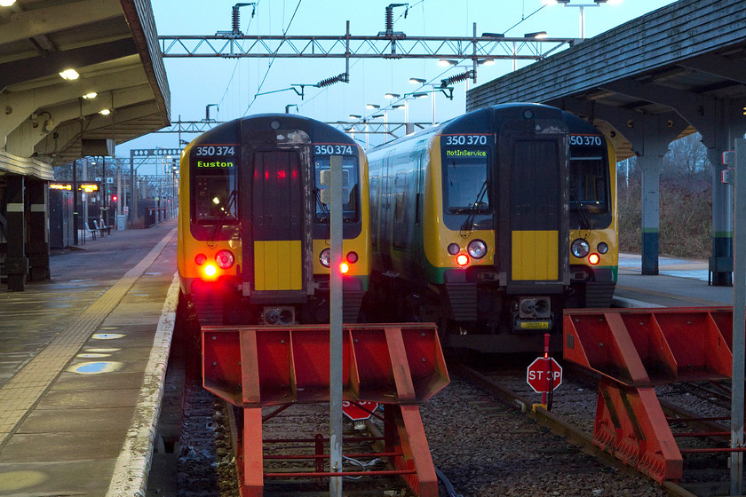 350374 & 350370, stabled, Northampton station 
 The two north-facing bay platforms at Northampton do not see a huge amount of use. Out of hours, they are used for stabling as shown here in the half-light of a cold March morning with 350374 and 350370 awaiting their next duties. 
 Keywords: 350374 350370 stabled Northampton station