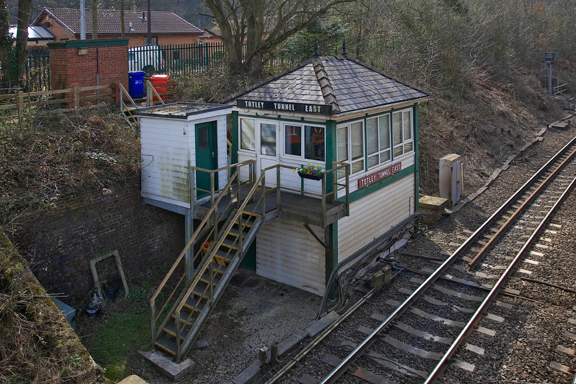 Totley Tunnel East signal box (Midland, 1893) 
 The delightful Totley Tunnel East signal box is pictured nestling in the cutting just below the footbridge that I am standing on. Despite the 1893 Midland Railway structure being modernised in 2006 it still retains a lot of its original character. The UPVC cladding is looking in need of a clean but if that is all the maintenance that it needs then I suppose maintenance costs will be a lot lower. The wooden nameboard looks to be the genuine article as do the finials atop the hipped slate roof. 
 Keywords: Totley Tunnel East signal box