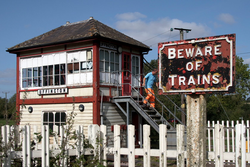 Uffington signal box (Mid. 1909) 
 I have taken a number of photographs of Uffington signal box over the years with my first one in August 1981. Then it controlled semaphores but today it is a mere crossing box but a remarkable survivor nonetheless. In this view, complete with a former Midland cast sign, the crossing keeper is descending the steps to close the manually operated gates. Whilst in need of a lick of paint, having lost its finials and having horrible replacement steps, it is actually in better condition than when I first saw it all those thirty-nine years ago, see... https://www.ontheupfast.com/p/21936chg/30044135645/uffington-signal-box when it looked very tatty indeed. 
 Keywords: Uffington signal box Midland Railway