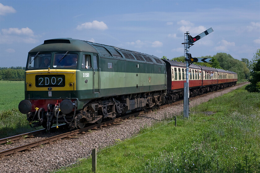 D1501, 12.50 Peterborough NV-Wansford (1M48), Ailsworth TL109979 
 In its authentic British Railways green livery D1501 looks right hauling a set of blood and custard Mk. 1 stock. It is seen hauling the 12.50 Peterborough Nene Valley to Wansford service that appears to be well patronised by enthusiasts! The train is seen approaching Wansford passing the fixed distant and outer home signal near the end of Ailsworth Lane. As 47402 the locomotive was extensively damaged in a head-on collision with a DMU at Leeds on 06.09.77 that, unfortunately, killed both drivers. 
 Keywords: D1501 12.50 Peterborough Nene Valley-Wansford 1M48 Ailsworth TL109979 47402 British Railways