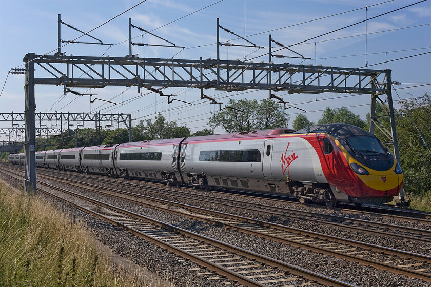 390153, VT 09.20 London Euston-Manchester Piccadilly (1H15), Bradwell SP831391 
 Under glorious summer skies, 390153 works the 09.20 Euston to Manchester Piccadilly Virgin West Coast service. Whist the clear blue sky allows strong and warm summer sunshine to beam down on the scene, unfortunately, due to the orientation of the line this photograph is rather backlit, a situation that will only worsen as time ticks on into the mid-morning. 
 Keywords: 390153 09.20 London Euston-Manchester Piccadilly 1H15 Bradwell SP831391 Virgin Pendolino