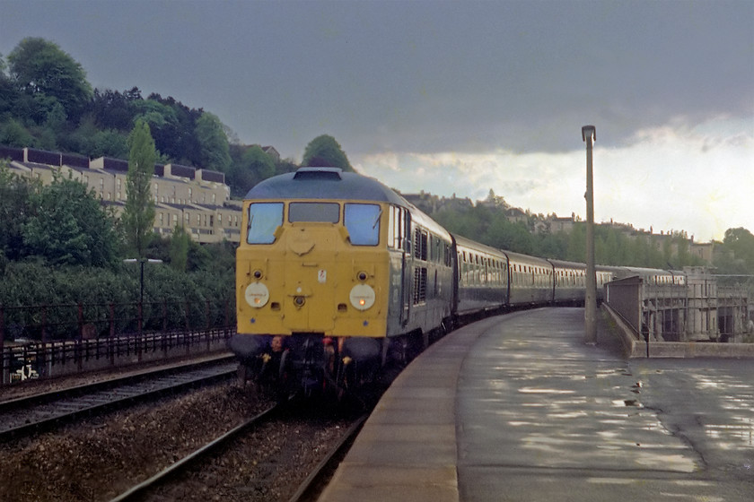 31117, unidentified Bristol Temple Meads-Portsmouth Harbour working, Bath Spa station 
 With the afternoon rain clearing 31117 is seen arriving at Bath Spa with the 17.15 Bristol Temple Meads-Portsmouth Harbour. I remember that this caused some excitement as a 'toffee apple' or 'skinhead' Class 31 were rare visitors to the Bristol area. I particularly like the lighting in this shot. It breaks all the rules by looking into the light but the reflections and contrast that make it a cut above the others I was taking at this time on the Exa camera. I took this train from Bath back home to Bradford-on-Avon. 
 Keywords: 31117 Bristol Temple Meads-Portsmouth Harbour Bath Spa station Toffee Apple Skinhead