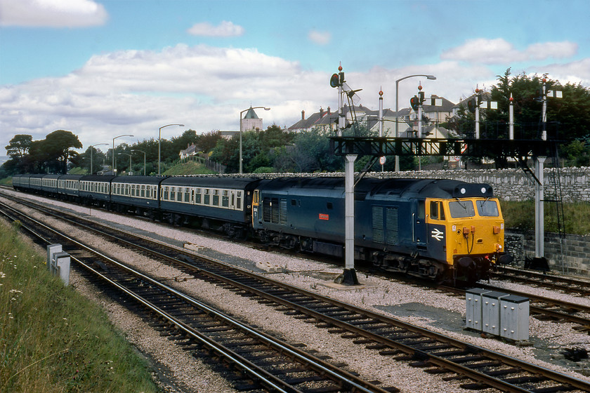 50011, unidentified down working, Aller Junction 
 Unfortunately, the sun has gone behind an errant cloud at Aller Junction. 50011 'Centurion' is well into its stride leading a long rake of Mk. 1 stock as gets a good run at Dainton bank passing under Aller's fine gantry. This locomotive had another seven years in service being the first member of the class to be withdrawn in February 1987. 
 Keywords: 50011 unidentified down working Aller Junction Centurion