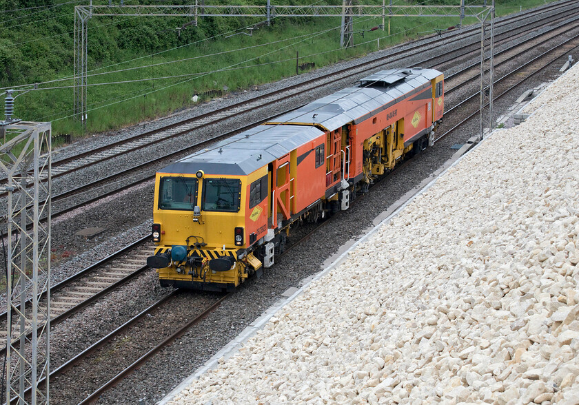 DR73923, 11.54 Coventry Yard-Watford London Concrete (45L), Ashton Road bridge 
 Colas 08-4x4/4S-RT switch and crossing tamper DR73923 runs past Roade about to pass under Ashton Road bridge making the relatively short journey from Coventry to Watford. This particular working was now running nearly an hour late having been held at Rugby even disappearing off the Open Train Times map leading me to think it had been capped or gone off route somewhere? Suddenly, it was reactivated and reappeared again so I am not too sure what went on there? 
 Keywords: DR73923 11.54 Coventry Yard-Watford London Concrete 45L Ashton Road bridge Colas Tamper