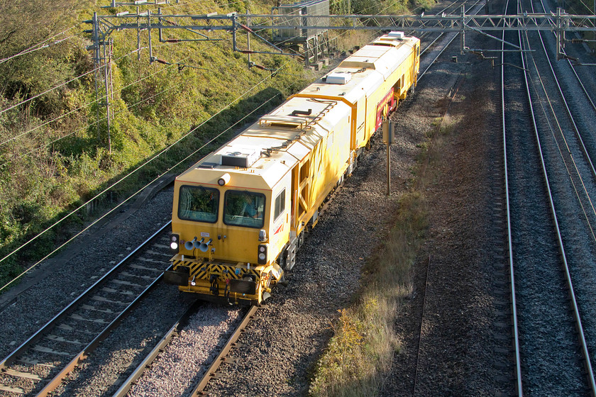 DR73118, 10.32 West Ealing Plasser Sidings-Crewe PAD, Victoria Bridge 
 To me, there appears to be an increasing number of the movement of these track machines around the network? Here, DR73118 trundles past Victoria Bridge just south of Roade making the 10.32 Ealing to Crewe move. Unfortunately, despite the amazing quality of modern digital equipment, it could not quite cope with the extreme tonal range from the shadows of the fast lines up to the bright yellow of the sun-drenched roof of the track machine. 
 Keywords: DR73118 10.32 West Ealing Plasser Sidings-Crewe PAD Victoria Bridge