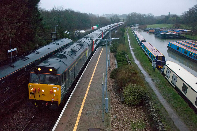 50008, outward leg of Shooter's Swansong, 04.52 Derby-Hinksey Yard (1Z20, 3L), Heyford station 
 In abysmal lighting at Heyford 50008 'Thunderer' heads south leading the outward leg of Shooter's Swansong that left Derby, running as 1Z20, at the unearthly hour of 04.52! If the morning had dawned as it had the previous day with clear skies this picture would have looked a whole lot better but the weather did not play ball, of course! 50008 'Thunderer' is currently owned and operated by the rail services solutions group Hanson and Hall. Notice GWR's 165124 paused on the down platform. Unfortunately, Andy had opted for the platform end shot of the charter so the 08.07 Didcot to Banbury all stations stopper did get in the way a little but he was not too disappointed as it was never going to have been a master shot was it really? 
 Keywords: 50008 outward leg of Shooter's Swansong 04.52 Derby-Hinksey Yard 1Z20 Heyford station Thunderer