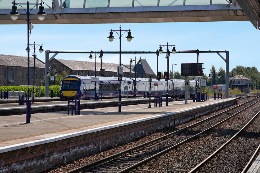 170470, SR 11.18 Glasgow Central-Alloa (2N67), Stirling station 
 Changes are on their way! With one lone electrification gantry in place at Stirling, the march northwards of the wiring continues whilst the one hundred and fourteen-year-old signal box in the background lives on; for the moment anyway controlling the newly installed colour lights. 170470 arrives at Stirling with the 11.18 Glasgow Central to Alloa working. Alloa is on the fright only line that continues along beside the Fife estuary to Dunfermline. It serves the huge Longannet coal-fired power station but with its imminent closure, the future of the line beyond Alloa is in question. 
 Keywords: 170470 11.18 Glasgow Central-Alloa 2N67 Stirling station ScotRail