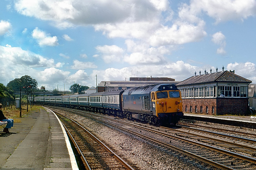 50008, 08.34 Penzance-London Paddington, Tiverton Junction station 
 Tiverton Junction Station was situated some five miles from the town of Tiverton. It was actually located in the village of Willand, a quiet place until the arrival of the M5 motorway no doubt! 50008 'Thunderer' takes the centre road through the station with the 08.34 Penzance to London Paddington. Behind the engine, the large signal box is seen on the up platform. The station was not particularly well placed and after steady rationalisation over the years, it was eventually closed in 1986. The new Tiverton Parkway was opened some three miles north of the old station but, ironically, now even further from the town of Tiverton! 
 Keywords: 50008 08.34 Penzance-London Paddington Tiverton Junction station