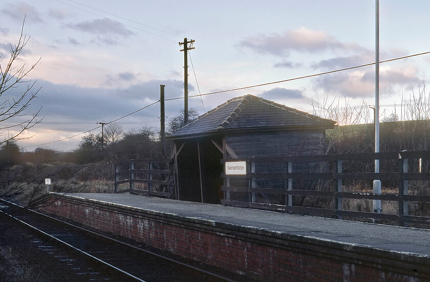 Skelmanthorpe station 
 BR's policy on lines that it wanted to close during the 1970s and 1980s was to deliberately run them down thus dissuading passengers from using them to then fortify their case for closure. A policy where this was used to good effect was the Clayton West branch line that BR eventually managed to shut on 22.01.83 some two years after this picture of a run down Skelmanthorps station was taken. Even after passenger services were withdrawn the line remained open for another ten months serving the adjacent Emley Moor collieries. In this view, looking due west, the remaining station structure, a rickety old timber waiting room, appears to be subsiding given its jaunty angle. A short time after this photograph was taken it was burnt down. Today, trains now run along the trackbed once again with a new station constructed as part of the Kirklees light railway that runs between Clayton West and Shelley. The land in the background that was where the aforementioned colliery was located now houses industrial units and a new housing development. 
 Keywords: Skelmanthorpe station