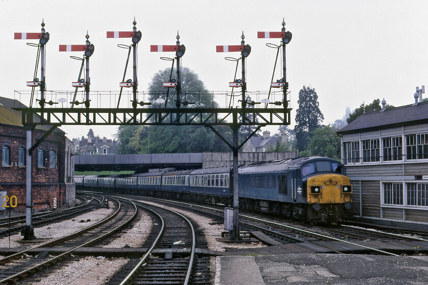 45061, 14.15 Paignton-Oxford (1A45), Newton Abbot station 
 Seen a little earlier on the sea wall, see.... https://www.ontheupfast.com/p/21936chg/30023741506/x45061-07-28-derby-paignton-1V62 split headcode 45061 returns from Paignton with the 1A45 14.15 service to Oxford. It is seen entering Newton Abbot's past the West signal box and the absolutely magnificent down gantry controlling westward movements from the station. This is strange working and I am not at all sure of its routing and if the Peak takes the train to whole way. I suspect that the Peak would have come off at Bristol and then the service would continue along the GWML to take the Didcot West curve with Class 47 in charge; advice anybody? 
 Keywords: 45061 14.15 Paignton-Oxford 1A45 Newton Abbot station Peak