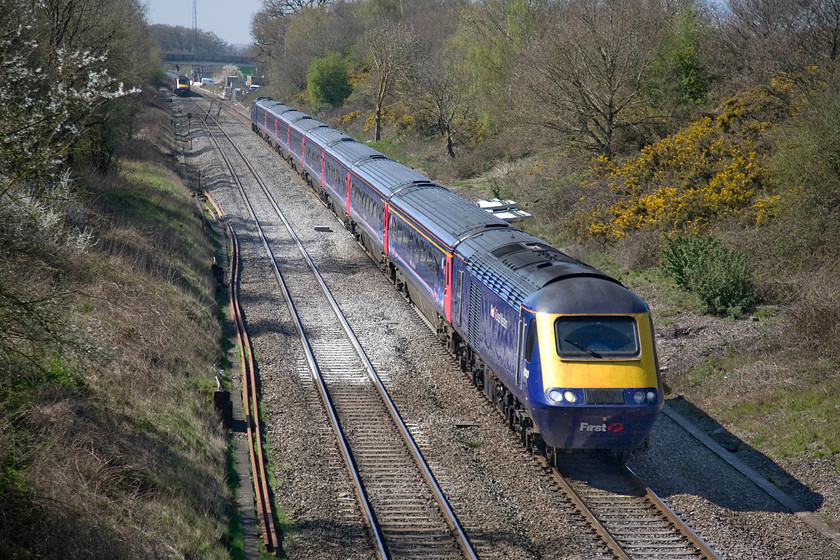 43130, GW 12.55 Cardiff Central-London Paddington (1L60), Baulking 
 As the 13.15 Paddington to Cardiff hst service heads west, 43130 leads the 12.55 from Cardiff eastbound. The trains have just passed the Uffington crossovers, one of which can be seen between the two trains. The new bridge, built to accommodate the 25kv wiring, which carries a minor road over the line can be seen in the very distance. However, photographic opportunities from it are limited as it has the ridiculously high anti-suicide parapets! 
 Keywords: 43130 12.55 Cardiff Central-London Paddington 1L60 Baulking Great Western HST