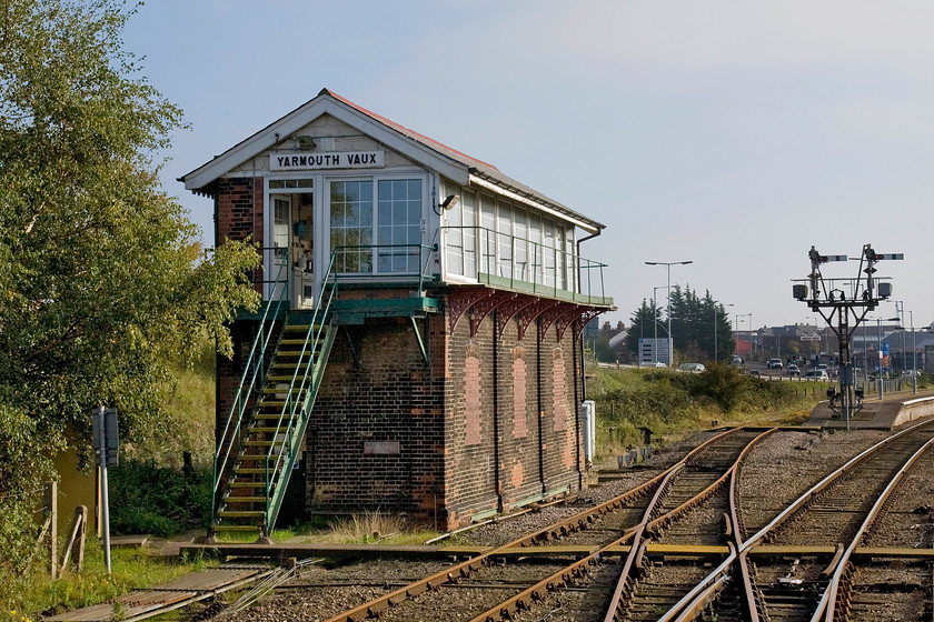 Yarmouth Vauxhall signal box (GE, 1884) 
 The superb Yarmouth Vauxhall signal box is seen from the droplight as the 12.36 from Norwich arrives at the station. It is a magnificent Great Eastern structure dating from 1884 that has thankfully been largely spared the scourge of crass 'modernisation' in the form of an inappropriate style of UPVC windows, cladding and a tin roof! Unfortunately, the Type 4 box that boasts a sixty-three lever Saxby and Farmer frame is doomed with the heavily delayed resignalling of the Wherry lines about to render it redundant. I sincerely hope that that the bulldozer and wrecking ball will not simply wipe it away but that it is sensitively dismantled and rebuilt somewhere on a heritage line. Notice the starter bracket signal on the platform ends with its illuminated route describers silhouetted against the lovely autumn sky. 
 Keywords: Yarmouth Vauxhall signal box Great Eastern