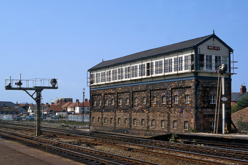 Rhyl No. 2 signal box (LNW, 1900) 
 The grand Rhyl Number 2 signal box was (and still is as it still stands) a L&NWR Type 4 structure dating from 1900. It replaced an earlier box when the railway along the North Wales coast was expanded with it largely quadrupled along its entire length. The box still stands as it is Grade II listed but during my last visit I found it boarded up and festooned with ivy having been closed in March 1990 with control moving to Number 1 box. Also of interest is the restricted height latticed bracket signal to the left of the photograph. This carries a circular banner repeater for the up fast line operated by Number 1 box located at the other end of the station behind me. 
 Keywords: Rhyl No. 2 signal box L&NWR