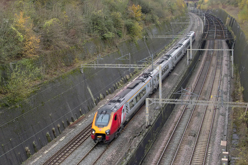 Class 221, VT 12.50 Birmingham New Street-London Euston (1B21, 12L), Roade cutting 
 An unidentified class 221 Voyager passes through the northern end of Roade cutting forming the 1B21 12.50 Birmingham New Street to Euston. In this view of the cutting, taken from the isolated Thorpe Wood bridge, the colloquially named 'birdcage' is seen spanning the up and down slow lines. This was installed to strengthen the retaining walls after the 1890 collapse. In the early 1960s the steel framework was raised to accommodate the 25kv wiring. 
 Keywords: Class 221 12.50 Birmingham New Street-London Euston 1B21 Roade cutting