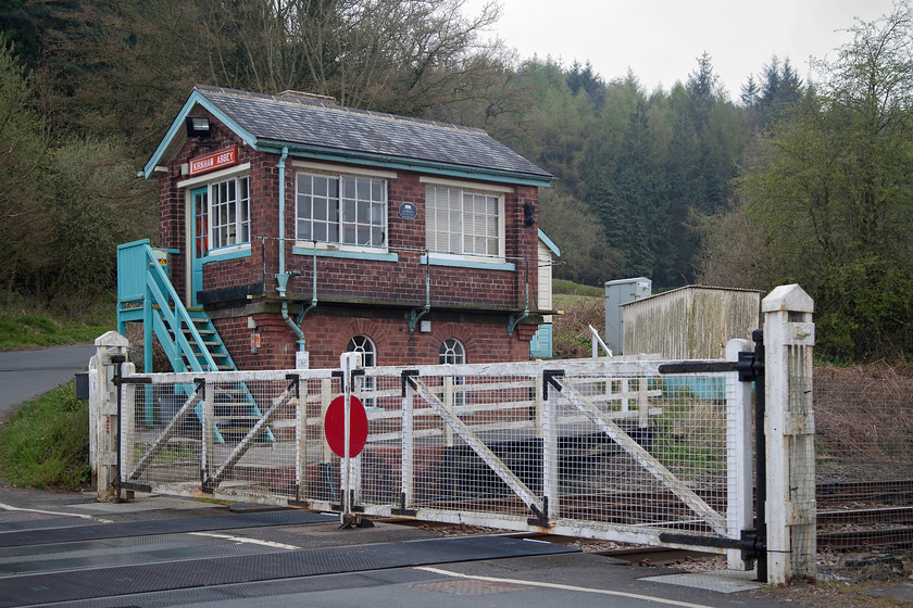 Kirkham Abbey signal box (NE, c.1873) 
 The delightful Kirkham Abbey signal box and its mechanical gates are seen in the gathering evening gloom. The box is a North Eastern Railway structure dating from circa 1873 built signal box was built type S1a design and it contains a McKenzie & Holland sixteen-lever frame. The box is a grade II listed structure and according to Historic England it is built in "red brick with slate roofs. The ground floor has 2 round-headed windows with glazing bars to the northeast front. A first-floor ashlar bond supports an iron bracketed balcony which runs around 3 sides of the building. This is reached up a set of external wooden steps. The north-east front has 2 large sliding sashes with glazing bars, side walls have a single similar window each, that to the south-east with a door as well. Rear front has a projecting central stack, flanked by single round-headed windows with glazing bars." *
* https://historicengland.org.uk/listing/the-list/list-entry/1315766 
 Keywords: Kirkham Abbey signal box