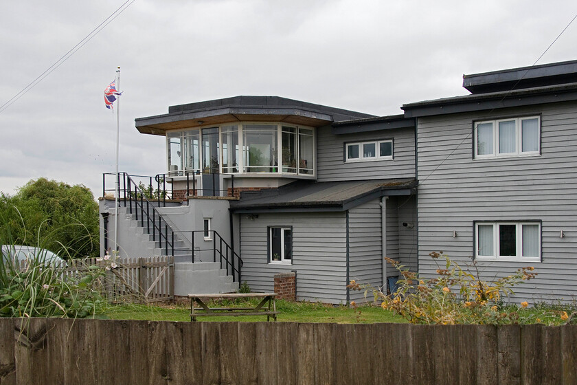 Former Murrow West signal box (LNER, 1950) 
 Looking more akin to a seaside residence the former 1950-built signal box at Murrow West is seen from the rear. The former GN & GE Joint line (that was shut in 1982) ran in front of the box between it and the trees. The also closed M & GN single-track route from Peterborough to Wisbech ran to the right of the box (in this view) crossing the GN & GE line on a flat crossing. This flat crossing was the site of a dramatic crash in the cold wartime winter of 1941 when two freights collided caused by frozen points. The derailing wagons demolished the old signal box located diagonally opposite the replacement structure seen here. Luckily, the signalman on duty survived allegedly (according to local legend) reporting to the accident inspector that he 'fancied a dollop of pickle in his sandwich' that he was eating at the time of impact. One of the crashed trains was conveying Branston pickle! I last visited the box in 1981 on my summer tour with Graham and stood in a very similar position to take this photograph, see....https://www.ontheupfast.com/p/21936chg/30046908474/murrow-west-signal-box-lner 
 Keywords: Former Murrow West signal box LNER 1950