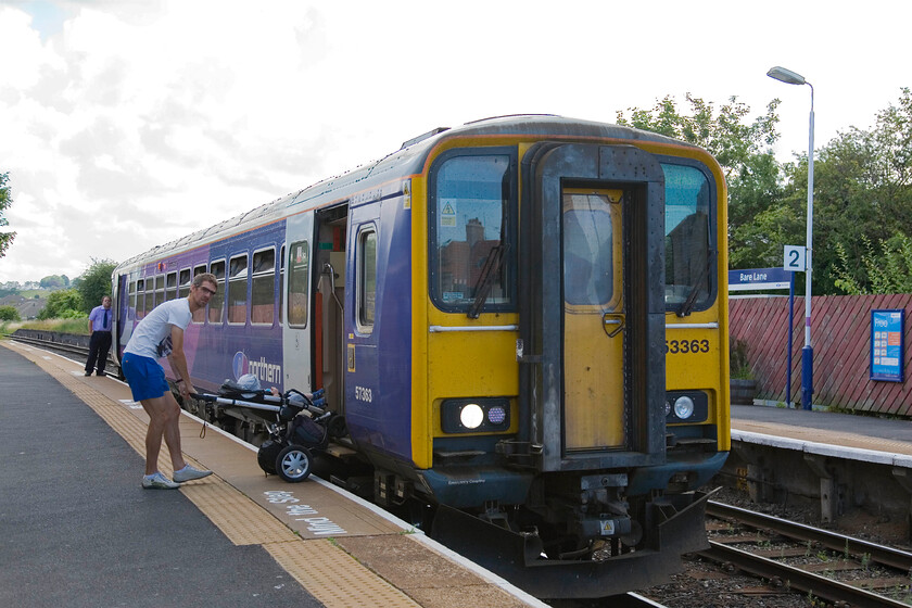 153363, NT 10.04 Lancaster-Morecambe, Bare Lane station 
 Bare Lane is a small station in a district of Morecambe served by local Northern Trains. 153363 is seen pausing at the station working the 10.04 Lancaster to Morecambe shuttle service. I cannot help but feel that the passenger easing the buggy off the train shares a passing resemblance to one of the Gallagher brothers; thoughts, please! 
 Keywords: 153363 10.04 Lancaster-Morecambe Bare Lane station Northern