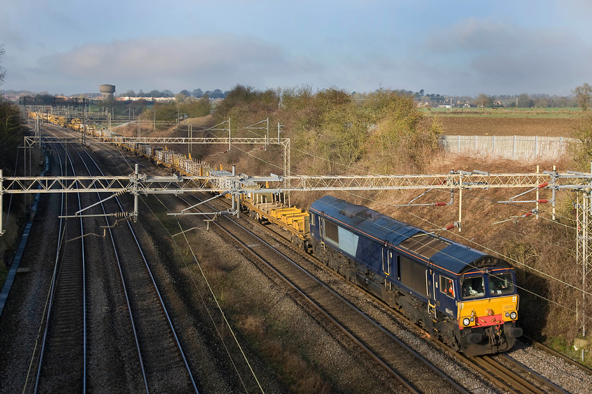 66415, 08.20 Birmingham International-Willesden Euroterminal, Victoria bridge 
 Under lovely winter skies, 66415 leads the 08.20 Birmingham International to Willesden Euroterminal infrastructure train past Victoria bridge on the southern WCML at Roade. This train was composed of a variety of engineering wagons with sections of reclaimed track as well as ballasting machines. Notice that the 66 is in DRS blue but has had its branding removed or covered over. 
 Keywords: 66415 08.20 Birmingham International-Willesden Euroterminal Victoria bridge