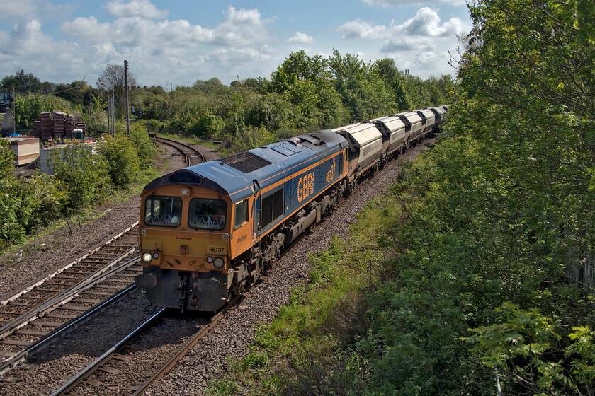 66737, 08.20 Middleton Towers-Monk Bretton Redfearns (6E96, 4E), March West Junction 
 Colloquially known as the 'Redfearns' the 08.20 Middleton Towers to Monk Bretton (Barnsley) passes March West Junction led by 66737 'Lesia'. This train conveys sand excavated from a site just east of King's Lyn utilising a spur of the former Great Eastern route that once linked through to Swaffham and Derham now kept open solely for that purpose. Interestingly, the same situation occurs at the other end of the train's route. Here it runs along a section of the former Midland route that once ran from Wath to Goose Hill Junction which I traversed in 1980, see... https://www.ontheupfast.com/p/21936chg/C372295804/x3-west-wilts-district-scout-special This freight accesses the Ardagh Glass plant at Monk Bretton from the north with the line open and maintained just for these trains. 
 Keywords: 66737 08.20 Middleton Towers-Monk Bretton Redfearns 6E96 March West Junction GBRf sand Lesia