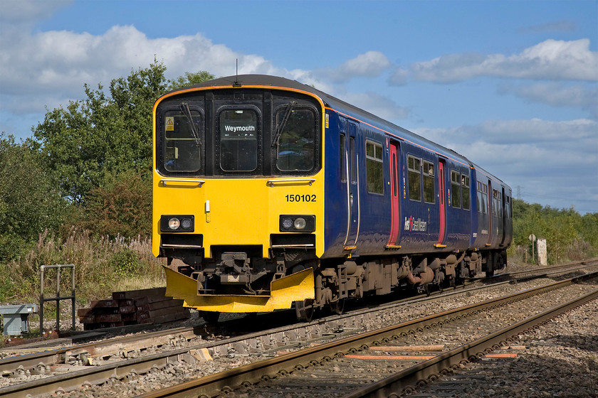 150102, GW 10.42 Gloucester-Weymouth (Cancelled from Castle Cary) (2O89), Blatchbridge Junction 
 150102 rejoins the West of England mainline at Blatchbridge Junction having taken the Frome divergence. Under a lovely autumn sky and in superb lighting the Sprinter is working the delayed 10.42 Gloucester to Weymouth. Unfortunately, the train was cancelled a short distance from here at Castle Cary. As with the previous photograph, I am in a safe position in a cage at a foot crossing. 
 Keywords: 150102 10.42 Gloucester-Weymouth Cancelled from Castle Cary 2O89 Blatchbridge Junction First Great Western FGW